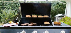 barbecue grill with burgers and buns on it